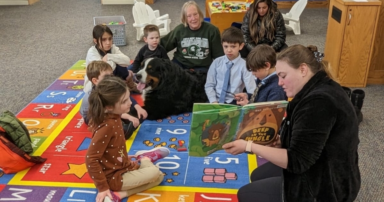 Group of children reading with therapy dog, Ben. 